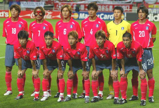 2002년 한일 월드컵 당시의 대한민국 축구 국가대표팀 선수들이 경기 전 단체 사진을 찍고 있는 모습.
선수들은 붉은색 유니폼을 착용했으며, 일부 선수는 고글(이을용) 착용 등으로 눈에 띈다. 뒤에는 관중석과 광고판이 배경으로 보인다. 골키퍼는 노란색 유니폼을 착용.